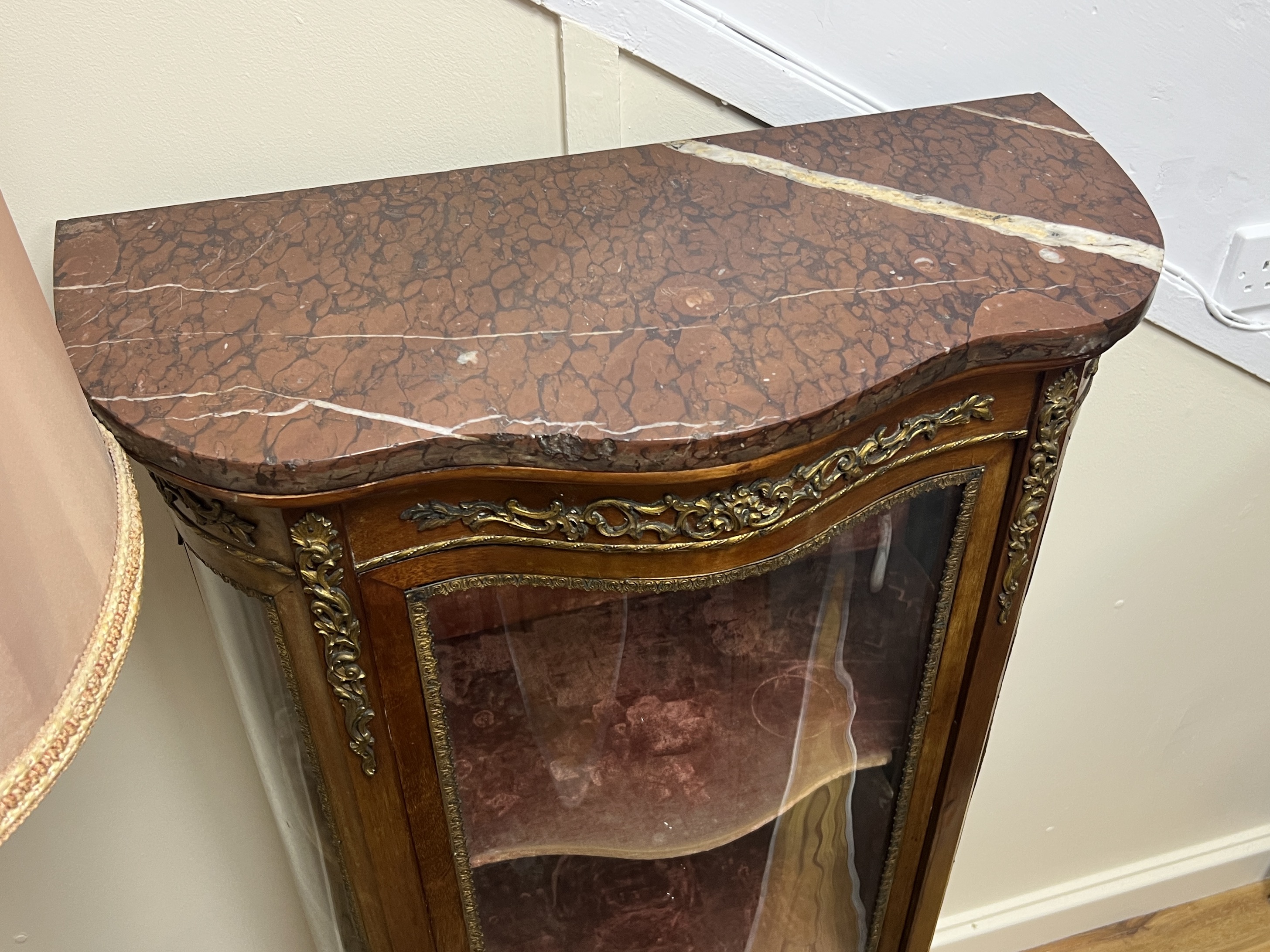 A Louis XVI style gilt metal mounted marble topped serpentine vitrine, width 70cm, depth 33cm, height 140cm